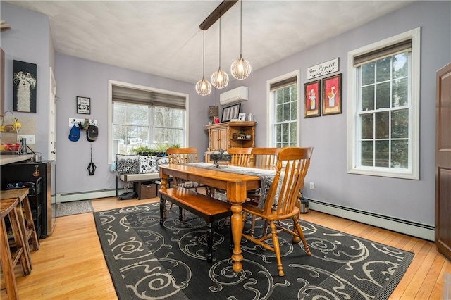 dining room featuring a baseboard radiator, a healthy amount of sunlight, and light wood finished floors