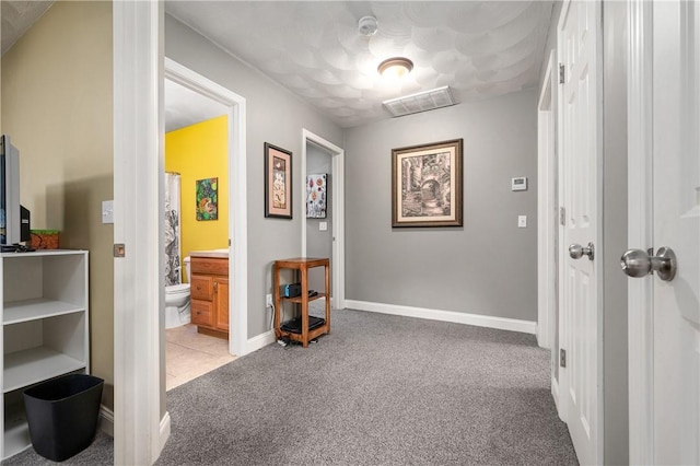 hall featuring carpet, visible vents, and baseboards