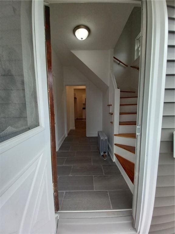 staircase featuring radiator and baseboards