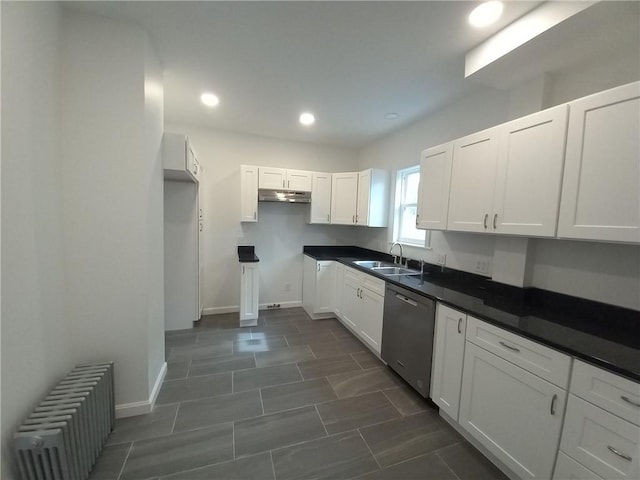 kitchen featuring radiator, stainless steel dishwasher, white cabinetry, a sink, and under cabinet range hood