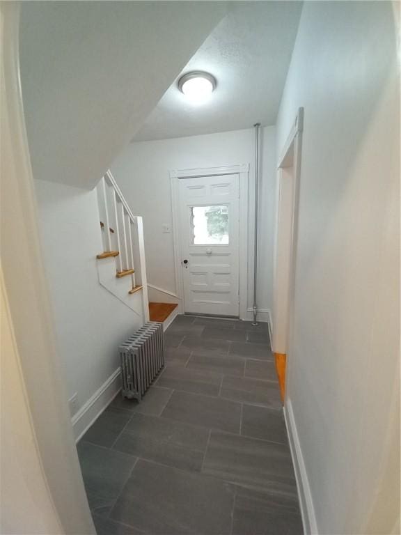 doorway featuring radiator heating unit, stairway, and baseboards