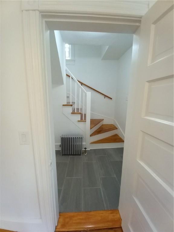 stairway with baseboards and radiator heating unit