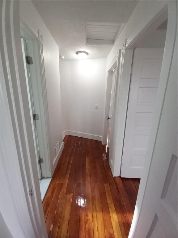 hallway with visible vents, hardwood / wood-style flooring, and baseboards