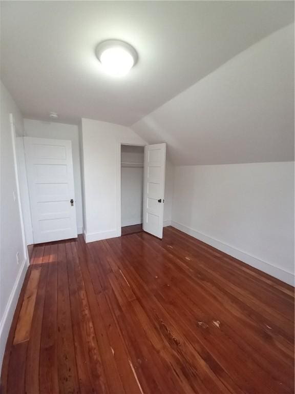 bonus room with baseboards, vaulted ceiling, and dark wood-style flooring