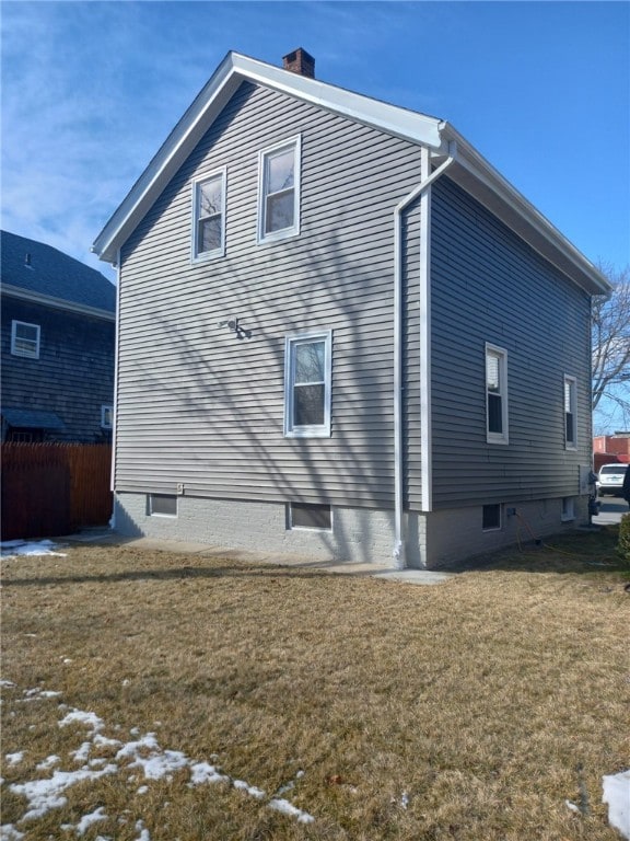 view of side of property with a lawn, a chimney, and fence