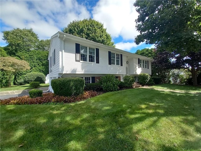 raised ranch with brick siding and a front yard