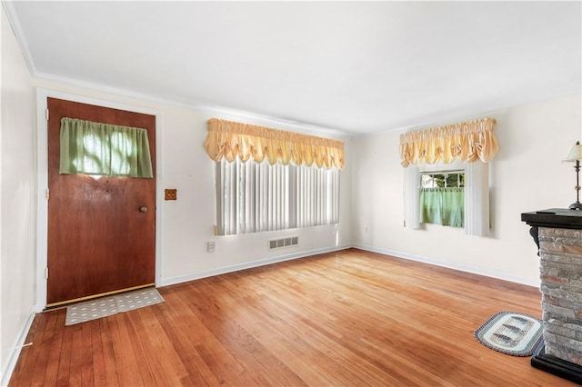 foyer featuring baseboards, visible vents, and wood finished floors