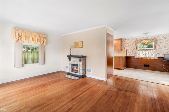 unfurnished living room with wallpapered walls, visible vents, baseboards, light wood-type flooring, and a fireplace