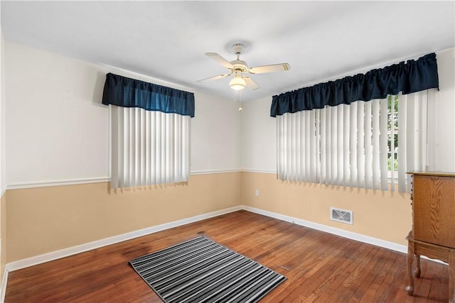 unfurnished room with ceiling fan, hardwood / wood-style floors, visible vents, and baseboards