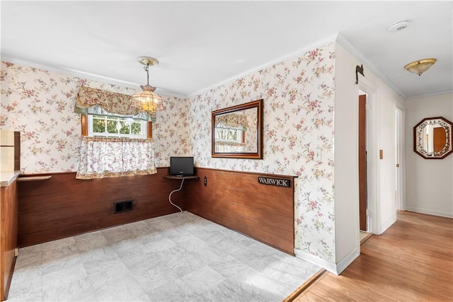 unfurnished dining area with ornamental molding, wood finished floors, baseboards, and wallpapered walls