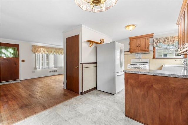 kitchen with white appliances, a sink, visible vents, light countertops, and brown cabinets