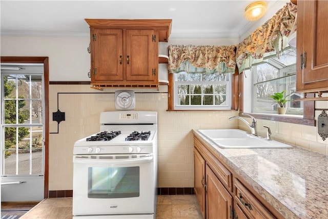 kitchen with crown molding, brown cabinets, white gas stove, and a sink