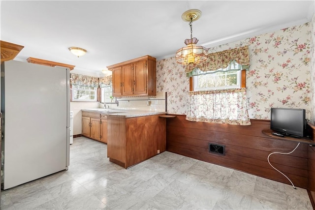 kitchen featuring freestanding refrigerator, wainscoting, a peninsula, and wallpapered walls