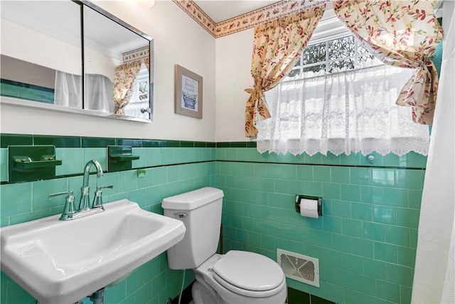 bathroom featuring a healthy amount of sunlight, visible vents, a sink, and toilet