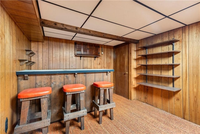 bar with carpet flooring, wood walls, and a bar