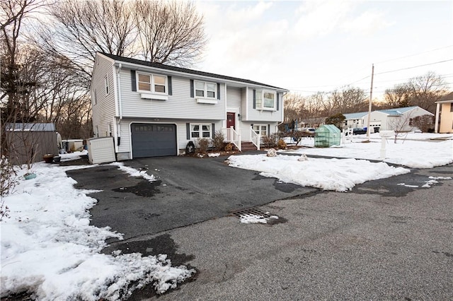 bi-level home with aphalt driveway and a garage