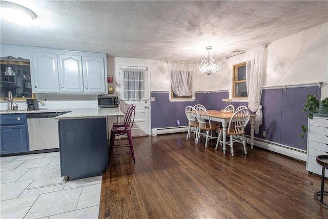 kitchen with a breakfast bar area, light wood-style flooring, stainless steel appliances, blue cabinetry, and baseboard heating