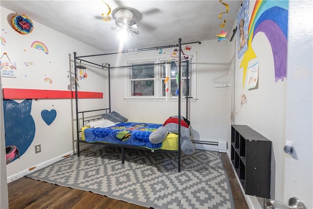 bedroom with a baseboard heating unit and wood finished floors