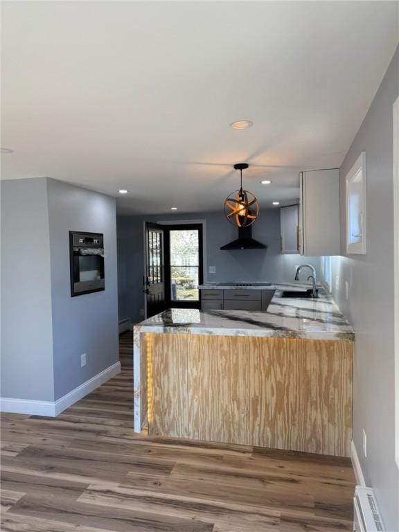 kitchen with oven, a sink, baseboards, and wood finished floors