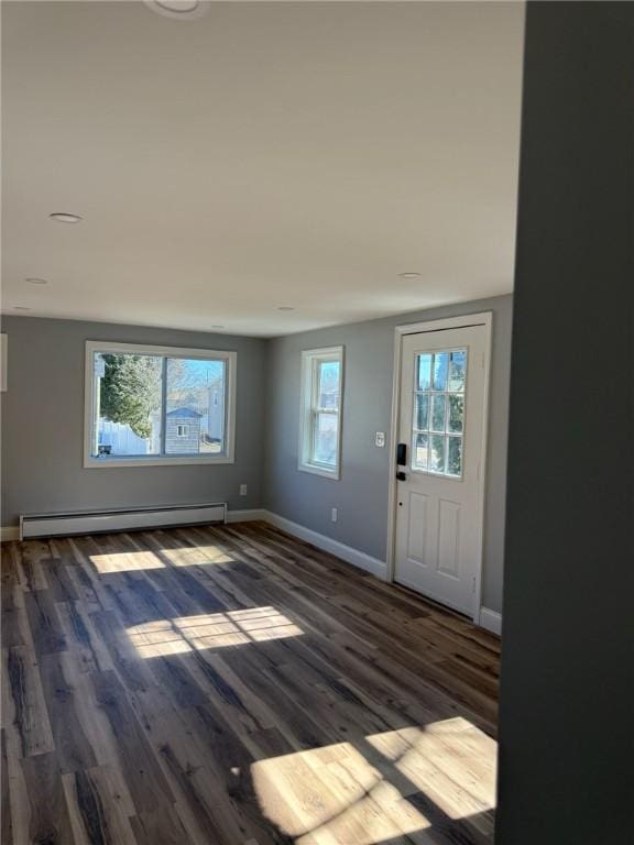 foyer with a baseboard heating unit, wood finished floors, and baseboards