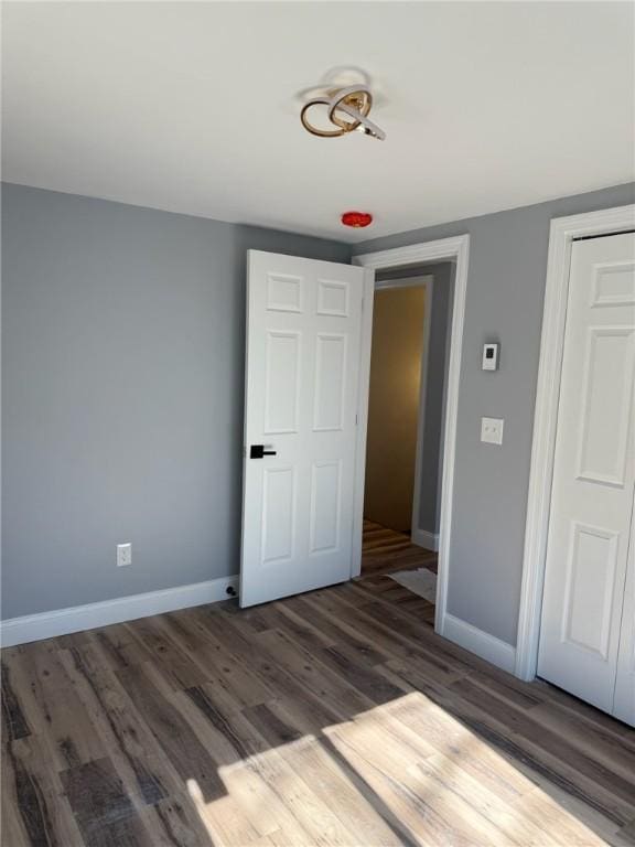 unfurnished bedroom featuring a closet, wood finished floors, and baseboards