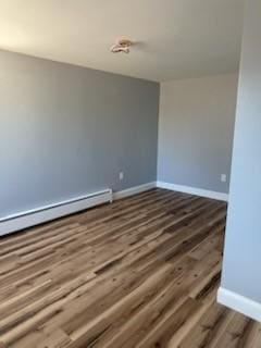 spare room with baseboard heating, baseboards, and wood finished floors