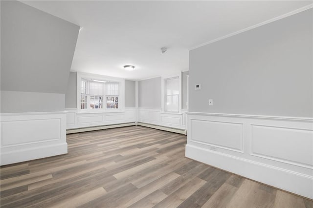 spare room with a wainscoted wall, a baseboard radiator, and wood finished floors