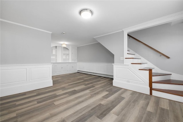 interior space featuring a wainscoted wall, wood finished floors, stairs, crown molding, and a baseboard heating unit