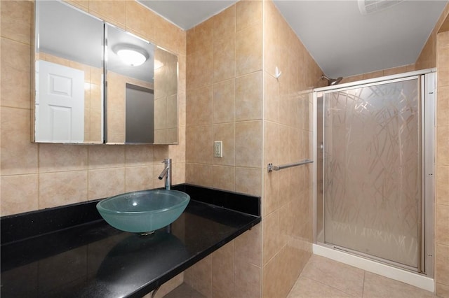 full bath with tile walls, backsplash, a stall shower, a sink, and tile patterned floors