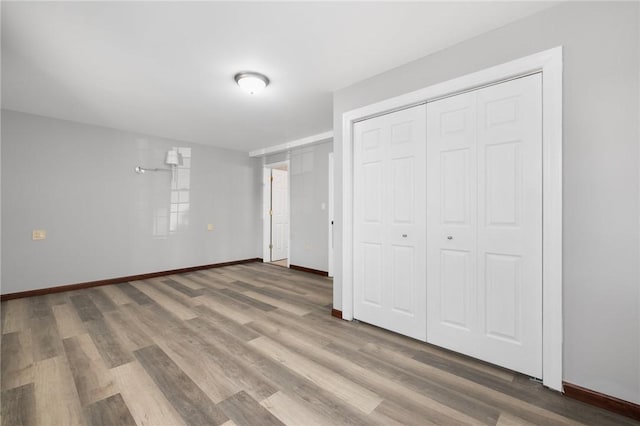 unfurnished bedroom featuring a closet, baseboards, and wood finished floors