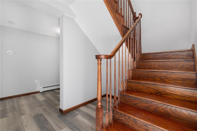 stairway with a baseboard radiator, wood finished floors, and baseboards