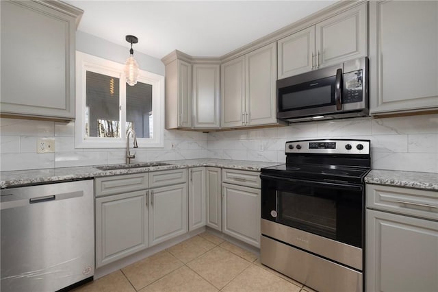 kitchen featuring pendant lighting, light tile patterned floors, backsplash, appliances with stainless steel finishes, and a sink