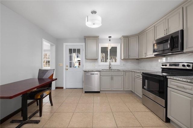 kitchen with light tile patterned floors, decorative backsplash, stainless steel appliances, and a sink