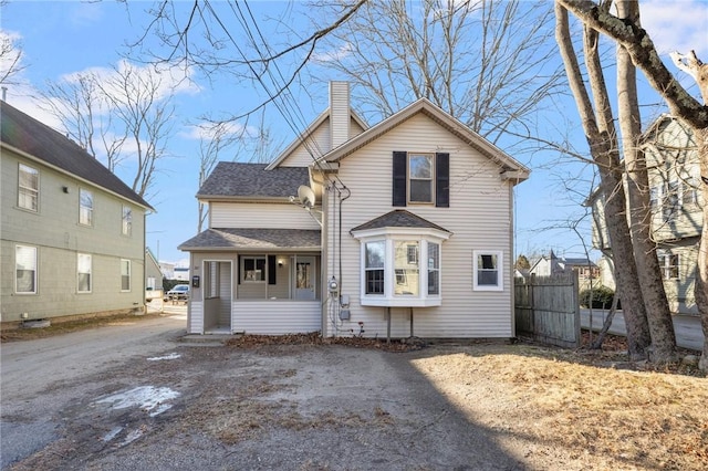 view of front of home with a shingled roof, fence, and a chimney