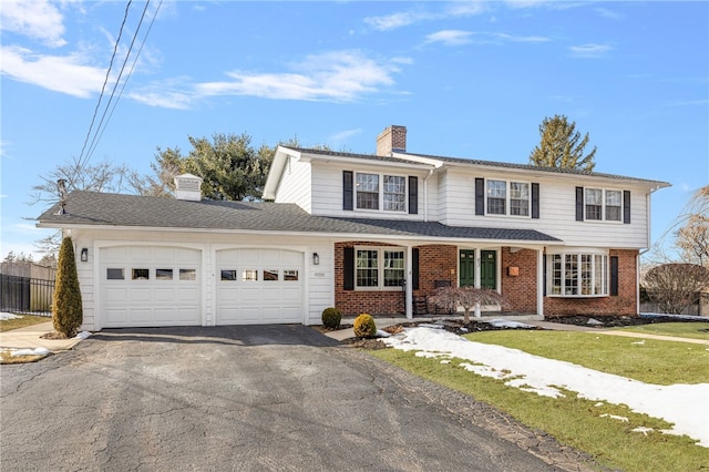 traditional-style home featuring brick siding, a chimney, an attached garage, fence, and driveway