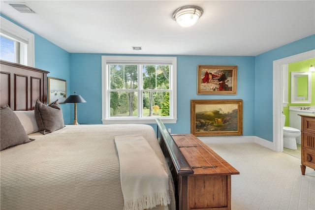 bedroom featuring ensuite bath, a fireplace, and visible vents