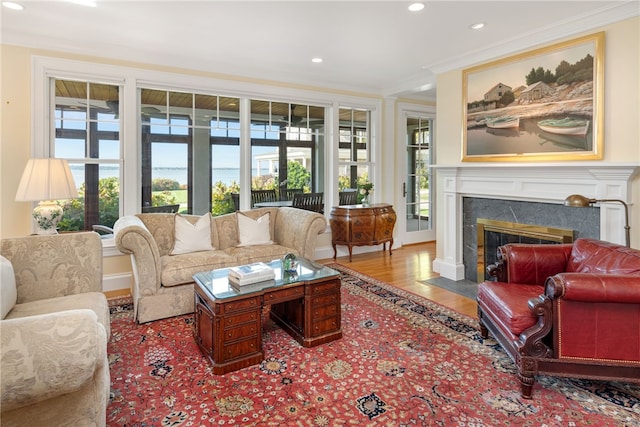 living area featuring a high end fireplace, a wealth of natural light, crown molding, and wood finished floors