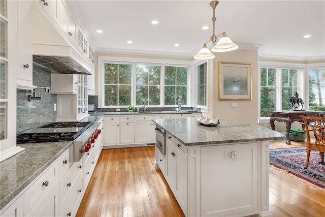 kitchen with stainless steel gas cooktop, light wood-style floors, a sink, and crown molding