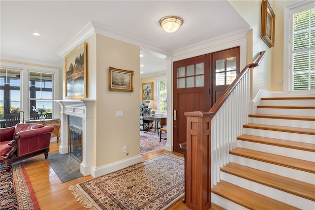 entrance foyer featuring a fireplace with flush hearth, wood finished floors, a healthy amount of sunlight, and stairs