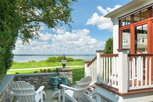 wooden terrace with a water view and a yard