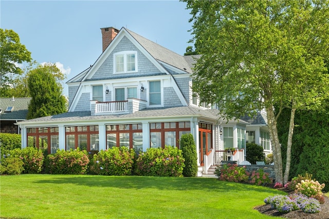 view of front of home with a shingled roof, a chimney, and a front lawn