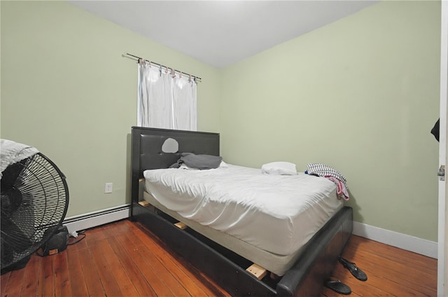 bedroom featuring hardwood / wood-style flooring, baseboards, and a baseboard heating unit