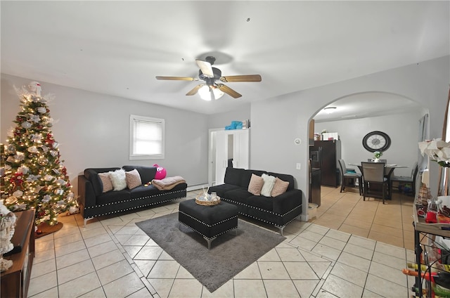 living room with a baseboard heating unit, ceiling fan, arched walkways, and light tile patterned floors