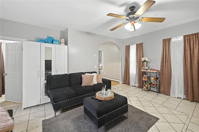 living room with baseboard heating, ceiling fan, arched walkways, and light tile patterned floors