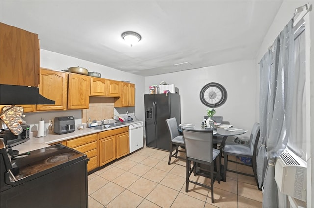 kitchen with under cabinet range hood, light countertops, light tile patterned floors, a sink, and black appliances