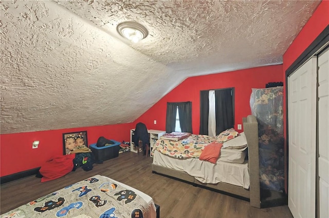 bedroom with a closet, a textured ceiling, vaulted ceiling, and wood finished floors