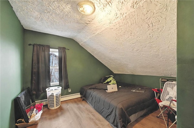 bedroom featuring a textured ceiling, lofted ceiling, a baseboard radiator, wood finished floors, and baseboards