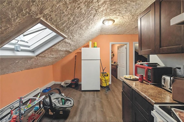 interior space featuring light wood-type flooring, vaulted ceiling with skylight, a textured ceiling, and baseboards