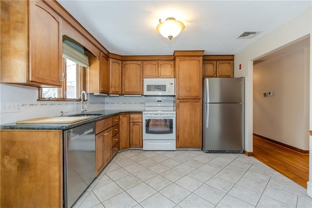 kitchen with stainless steel appliances, brown cabinetry, visible vents, and a sink