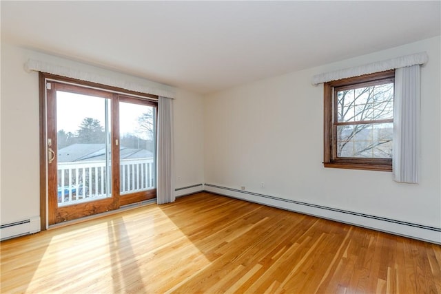 empty room featuring a baseboard radiator, light wood-style flooring, baseboard heating, and a wealth of natural light